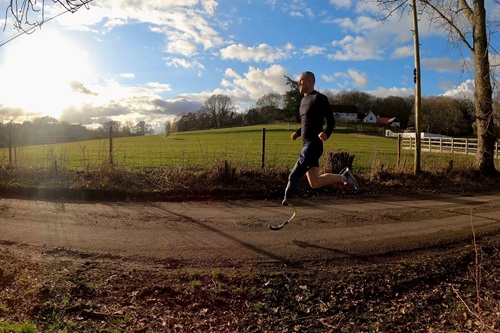 A blue sky, with a field and Michael running down a track